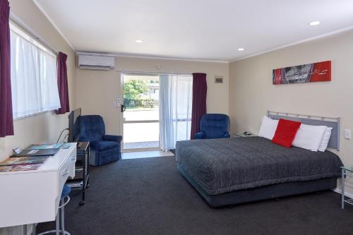 a bedroom with a bed and a desk and chairs at Livingston Motel in Whakatane