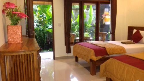 1 Schlafzimmer mit 2 Betten und einem großen Fenster in der Unterkunft Taman Puspa in Ubud
