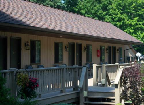 a house with a porch and a white railing at Tall Pines Motel in Lake George