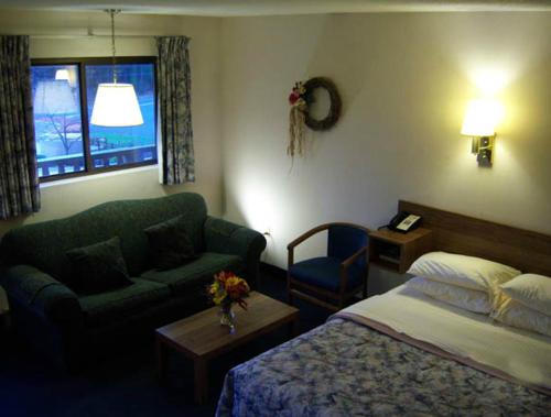 a bedroom with a bed and a couch and a chair at Tall Pines Motel in Lake George