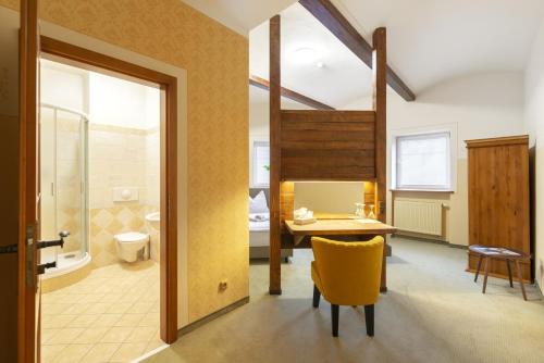 baño con mesa y silla amarilla en una habitación en Hotel U Simla, en Karlovy Vary