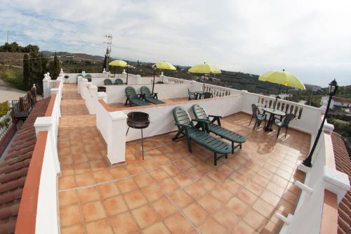patio z krzesłami, stołami i parasolami na dachu w obiekcie Apartamentos Rurales Santos w mieście Benajarafe