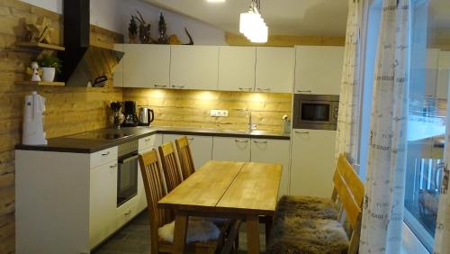 a kitchen with white cabinets and a wooden table at Appartement Alpenliebe in Rauris