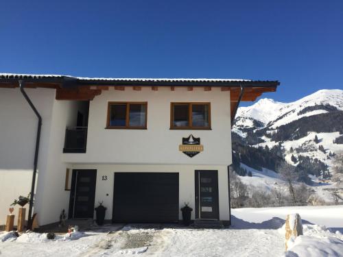 a house in the snow with mountains in the background at Appartement Alpenliebe in Rauris