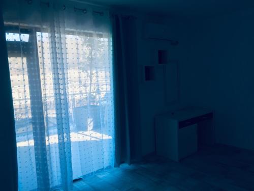 Habitación oscura con una ventana con cortinas y una mesa. en Апартаменти Романтика Кирково en Kirkovo