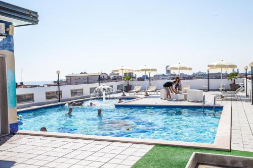 een zwembad op het dak van een gebouw met mensen erin bij Hotel Christian in Lido di Jesolo