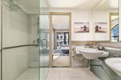 a bathroom with two sinks and a glass shower at Enormous CBD 1BR Unit with Parking by Zodiak Stays in Auckland