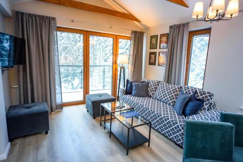 a living room with a couch and chairs and windows at Bukowa Dolina, Sun & Snow in Krynica Zdrój