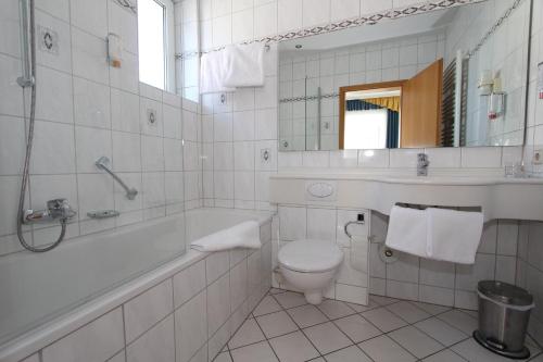 a bathroom with a tub and a toilet and a sink at Hotel Schoch, Trossingen in Trossingen
