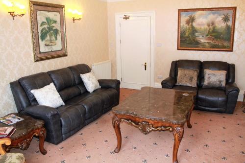 a living room with a leather couch and a coffee table at Tor Dean Guest House in Torquay