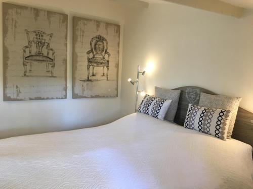 a bedroom with a large white bed with two pictures on the wall at L' Esmerand in Cotignac