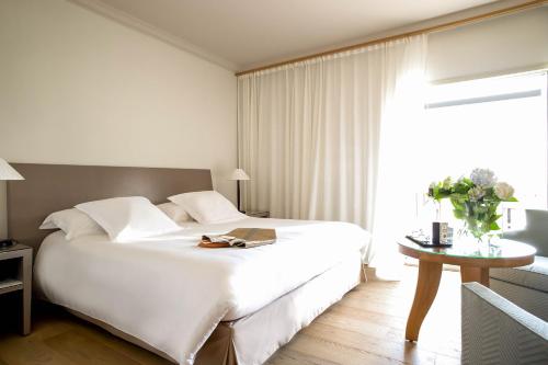a bedroom with a large white bed and a table at La Villa Calvi in Calvi