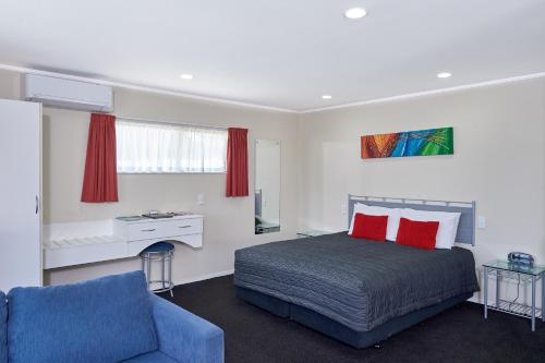 a bedroom with a bed with red pillows and a blue couch at Livingston Motel in Whakatane