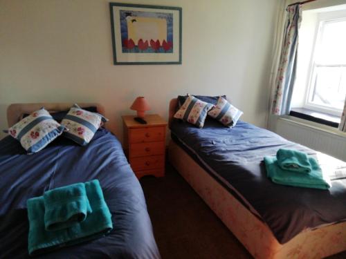 2 posti letto in una stanza con asciugamani verdi di The Royal Oak a Kington