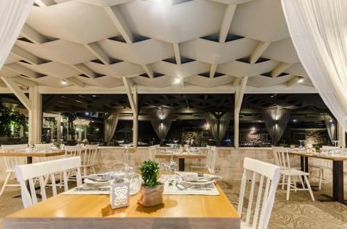a dining room with tables and chairs and a coffered ceiling at Pela Mare Hotel in Agia Pelagia
