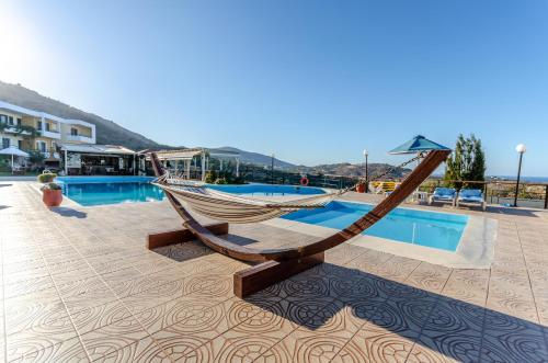 a hammock sitting on a patio next to a pool at Pela Mare Hotel in Agia Pelagia