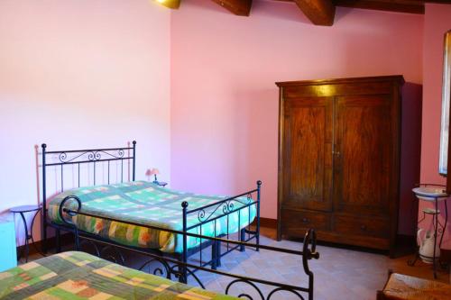 a bedroom with two beds and a wooden cabinet at Casale Poggio Colpiccione in Passignano sul Trasimeno