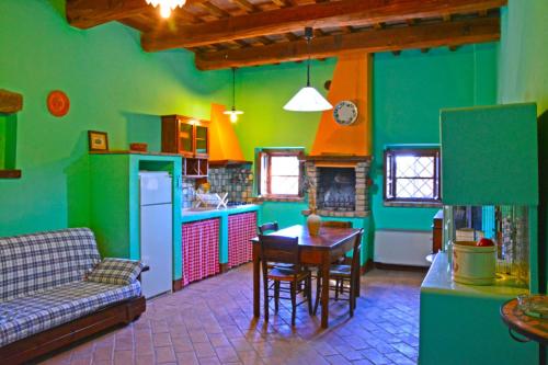 帕西尼亞諾特拉西梅諾的住宿－Casale Poggio Colpiccione，厨房设有绿色的墙壁、桌子和沙发