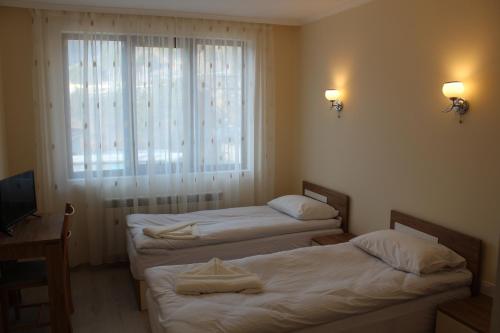 2 Einzelbetten in einem Zimmer mit Fenster in der Unterkunft Къща за гости Мишурови in Smoljan