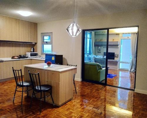 a kitchen with a island with two chairs and a kitchen with a couch at 21C Riviera Up Condominium in Pak Kret