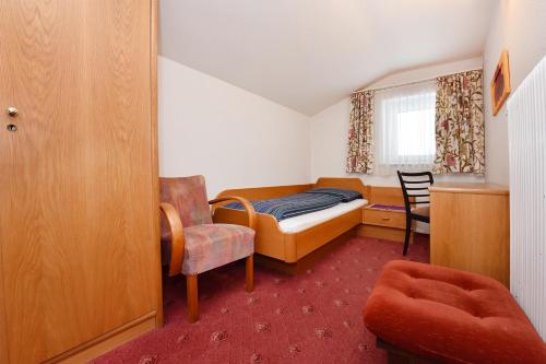 a small bedroom with a bed and a chair at Landhaus Fuchsenstube in Schruns-Tschagguns