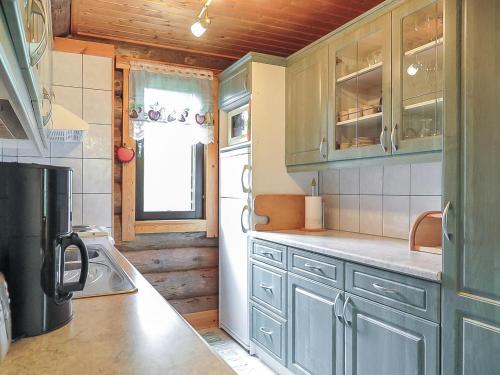 La cuisine est équipée de placards bleus et d'un réfrigérateur. dans l'établissement Holiday Home Jäkälä by Interhome, à Kyrö
