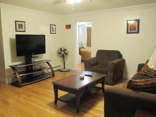 a living room with a tv and a couch and a table at Comerford's Ocean View Suites in Holyrood