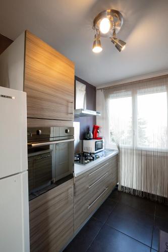 une cuisine avec des armoires en bois et un réfrigérateur blanc dans l'établissement Appartement Malya & parking privé, à Grenoble