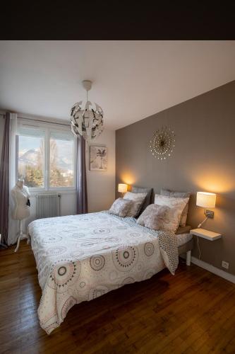 une chambre avec un grand lit et un lustre dans l'établissement Appartement Malya & parking privé, à Grenoble