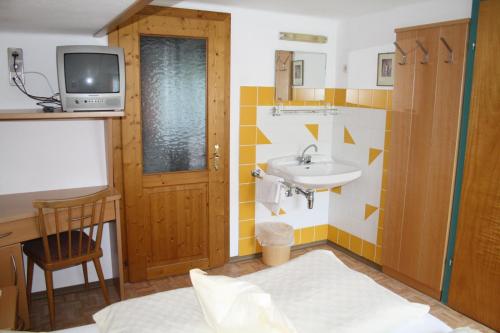 ein Badezimmer mit Waschbecken und einem Fernseher an der Wand in der Unterkunft Pension Wolf in Steindorf am Ossiacher See