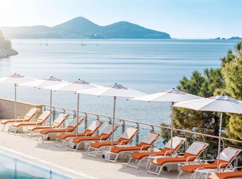 a row of chairs and umbrellas next to the water at Sun Gardens Dubrovnik in Dubrovnik