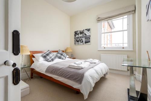 a bedroom with a bed with white sheets and a window at The Coach House Montpellier in Cheltenham