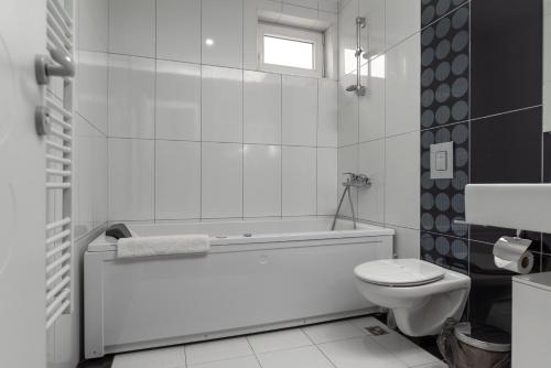 biała łazienka z wanną i toaletą w obiekcie Hotel Dolce International w mieście Skopje