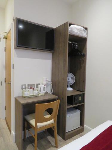 a room with a desk with a tv on the wall at Glendale Hyde Park Hotel in London
