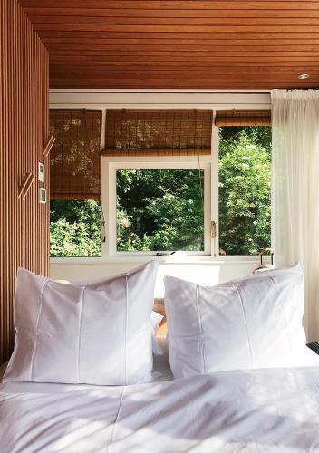 a bed with white pillows in a room with windows at SWEETS - Buiksloterdraaibrug in Amsterdam