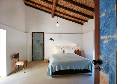 a bedroom with a large bed and a chair at Companhia das Culturas - Ecodesign & Spa Hotel in Castro Marim