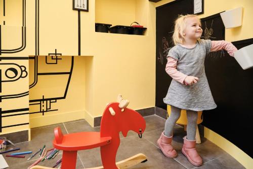 a little girl standing next to a red chair at ibis Styles Marseille Gare Saint-Charles in Marseille