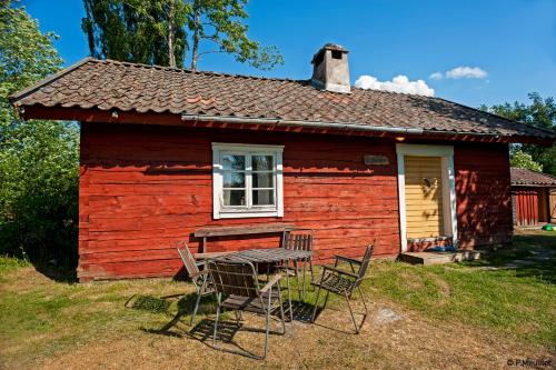 a red house with a table and chairs in front of it at STF Tivedstorp in Tivedstorp