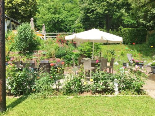 un jardín con sombrilla, sillas y flores en Hotel Sonnenhof, en Merzig
