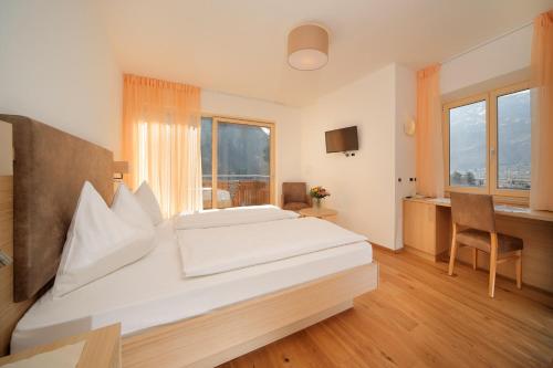 a bedroom with a large white bed and a desk at Hotel Neuhausmühle in Vilpiano