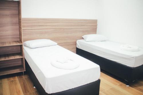 two twin beds in a room with wooden floors at Souza Reis Flat in São Thomé das Letras