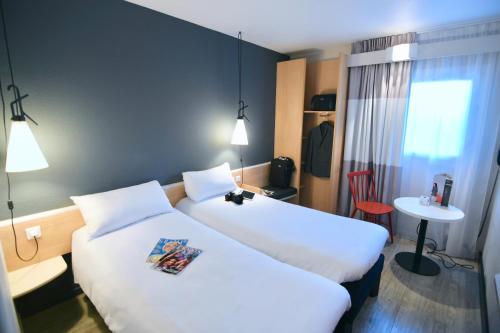 a hotel room with two beds and a table at ibis Maisons Laffitte in Maisons-Laffitte