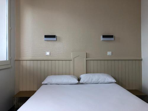a bed in a room with two pillows on it at HALT HOTEL - Choisissez l'Hôtellerie Indépendante in Lattes