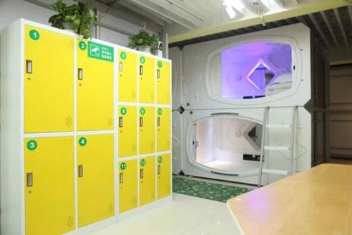 Cette chambre dispose de casiers jaunes et d'un lave-linge. dans l'établissement Wuhan Worry-free Capsule Hotel, à Wuhan