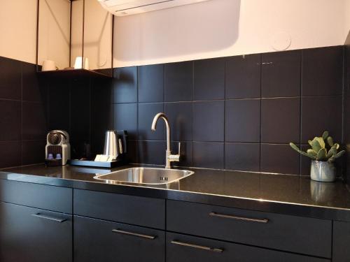a kitchen with a sink and black tiles at Boutique Suites Lisse - Schiphol in Lisse