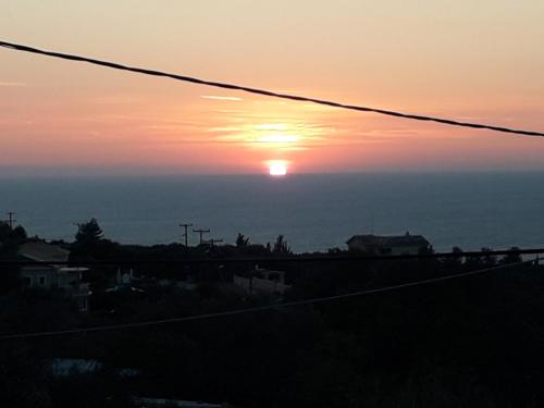 a sunset with the sun setting over the ocean at Monika Lefkada in Tsoukaladhes