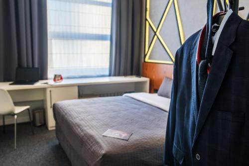 a hotel room with a bed and a suit hanging on the wall at Park Hotel Bydgoszcz in Bydgoszcz