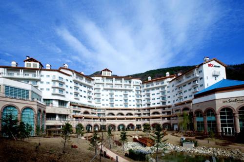ein großes weißes Gebäude mit einem Berg im Hintergrund in der Unterkunft STX Resort in Mungyeong