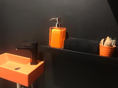 a bathroom with an orange soap dispenser and a sink at Les lofts de Styliste in Brussels