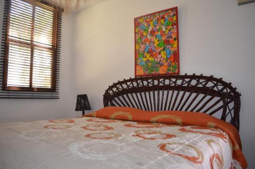 a bed in a bedroom with a painting on the wall at Hostería Ecológica El Faro in Salinas